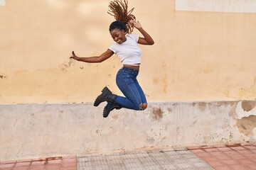 African american woman smiling confident jumping at street