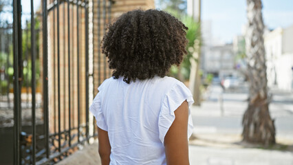 Black woman with curly hair outdoors in urban setting