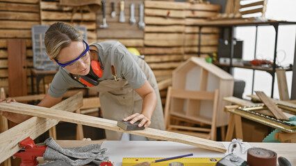 A focused woman sands a piece of wood in her carpentry workshop, embodying skill and creativity.