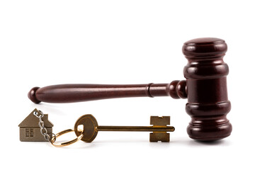 Judge's gavel and house key with a keychain in the form of a symbolic house on a white background
