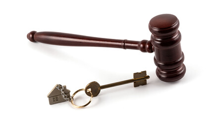 Judge's gavel and house key with a keychain in the form of a symbolic house on a white background