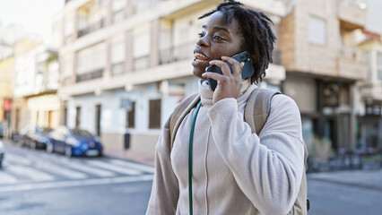 A joyful young black woman with dreadlocks talking on a phone, strolling on a sunny urban city...