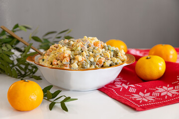 Russian salad, Olivier, shot on on a beautiful table next to the tangerines