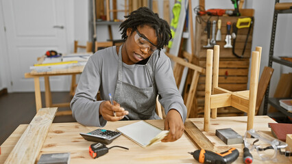 Woman in apron multitasking with phone and counting money in a workshop
