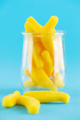 Yellow Swedish candy, chewy candies with banana flavor in glass on a blue background.