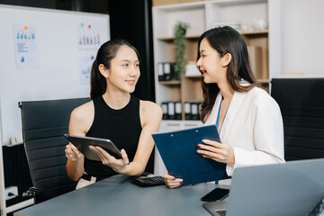 Businesswomen work and discuss their business plans. A woman employee explains and shows her colleague the results paper