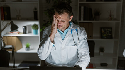 A stressed doctor in a clinic holding his head in frustration at his workplace.