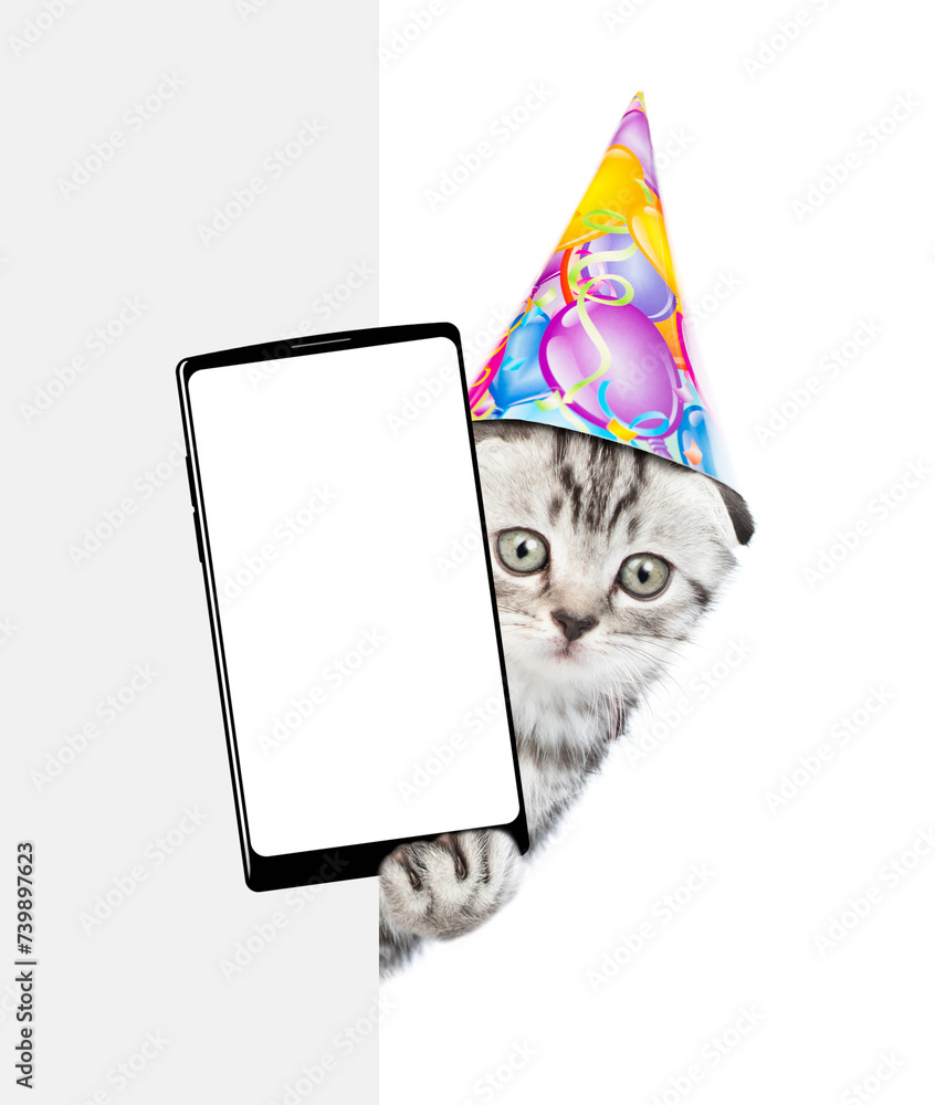 Aufkleber cute kitten wearing party cap shows big smartphone with blank screen from behind white banner. isola