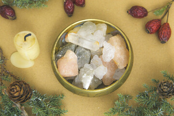 Kamienie i minerały w naczyniu miedzianym w otoczeniu roślinności i świecy.