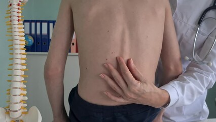 A young patient is seated on an examination table while a doctor carefully examines their spine