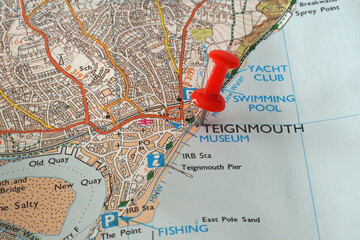 A close-up image of an ordnance survey map with a red map pin showing the town of Teignmouth in south Devon