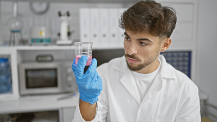 Serious young arab man scientist in lab, hands-on with test tube, engrossed in pivotal medicine...