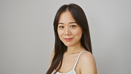 Portrait of a serene chinese woman with a subtle smile, standing against a white background, exuding elegance and simplicity.