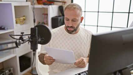 Handsome young man reporter charmingly presenting live radio show, vividly reading paperwork in...