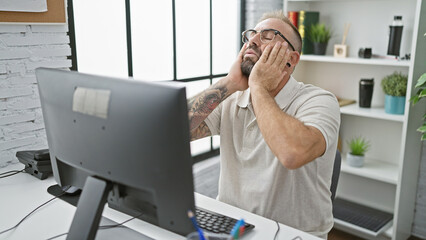 Stressed-out young business worker man feeling the heat of stress and exhaustion while working on...