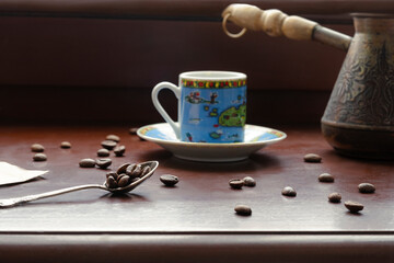 a coffee cup stands on a wooden surface next to a metal baton and a spoon, coffee beans are scattered nearby