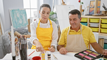 Passionate man and woman artists together recording an art tutorial, speaking whilst drawing in a cozy studio - an exciting lesson for aspiring painters