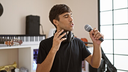 Handsome young hispanic man, an earnest music musician, concentrates on his performance, singing a...