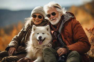 An old couple hiking an autumn mountain in winter with their pet dog