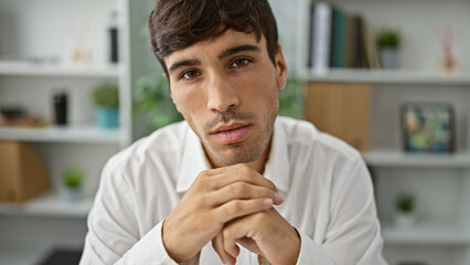 Handsome, young hispanic man sits at office table, embodying confidence. this serious business...