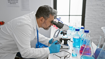 Young and passionate, a grey-haired hispanic man, embedded in his role as a scientist, engrossed in...