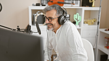 On air, young, handsome, grey-haired hispanic man, wearing headphones, broadcasting news from the...