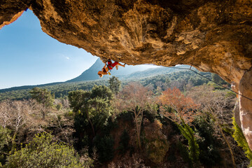 Girl climber on an overhanging rock. A sports woman climbs a rock against the backdrop of mountains. difficult movements in rock climbing. © zhukovvvlad