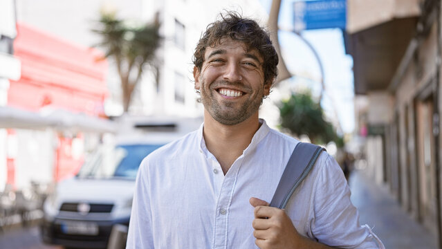 Handsome hispanic man with beard smiling in urban street setting