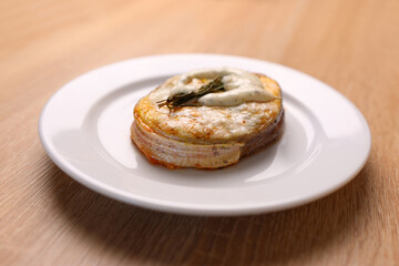 A freshly baked piece of salmon is placed on a plate and sauce is added