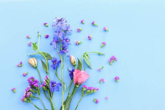 Top view image of pink and purple flowers composition over pastel blue background .Flat lay