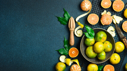 Orange fruit with green leaves on the dark blue background. Home gardening. Mandarine oranges....