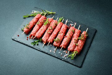 Lula kebab on skewers with spices in a black slate board on a stone background. Top view. - 739925806