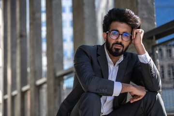 Young hindu businessman sitting on steps and looking tired and stressed