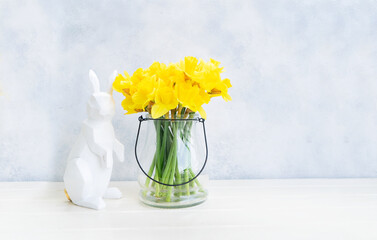 Easter Egg hunt with Easter white bunny and daffodils in vase