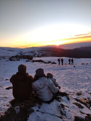 back view of a family in a sunset in the snowy mountain