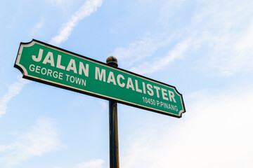 Macalister Road street sign in George Town, Penang, Malaysia with sunny bright blue sky as background.