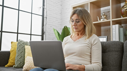 Mature caucasian woman using laptop in cozy living room