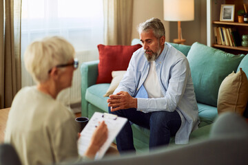 A worried mature adult male patient talking about his burdens to his psychotherapist while sitting...