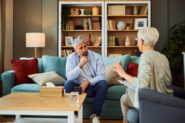 A distressed senior adult man pondering and listening to the advice from his psychotherapist with a...