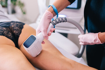 Woman getting a laser hair removal procedure on her thigh by a professional beautician in a beauty salon - 739936099