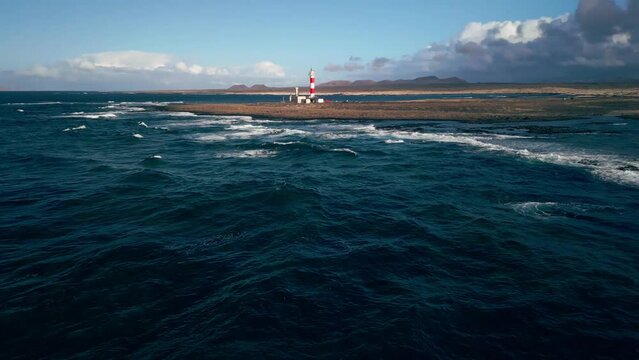 The 19th century red and white bands Faro del Tost&oacute;n lighthouse located on the northwest coast of Fuerteventura in the Canary Islands. A lighthouse against the background of the blue sky and the ocean