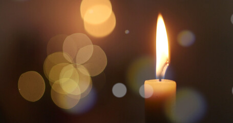 One candle flame at night with bokeh on a dark background