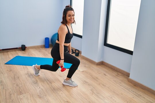 Young beautiful hispanic woman smiling confident training legs exercise at sport center