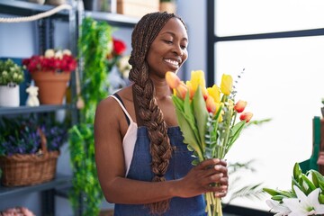 African american woman florist holding bouquet of flowers at flower shop
