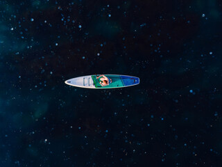 Obraz premium Woman on stand up paddle board in sea with a lot of jelly fish. Traveling on sup board in sea. Aerial view