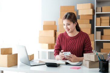 Startup SME small business entrepreneur of freelance Asian woman wearing apron using laptop and box...