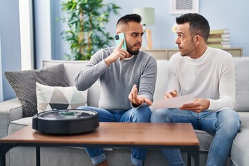 Two men talking on smartphone with technician vacuum robot service at home