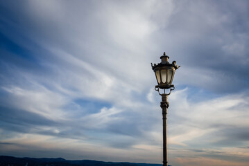 Historical lantern on the background of beautiful blue sky and clouds. Traditional vintage street lamp.