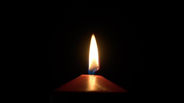 Super close-up of the burning flame of a wax candle wick in the dark. Religious background, concept of loss, death, tragedy, memory.