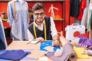 Young hispanic man tailor smiling confident make mark on cloth at atelier